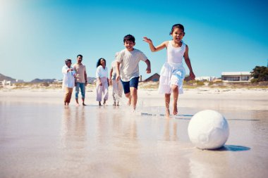 Aile futbolu, plaj tatili ve deniz kenarında özgürce koşan çocuklar. Futbol, genç kız ve ebeveynler yaz tatilinde okyanusta yürüyorlar. Çocuklarla birlikte kumsalda gülümsüyorlar..