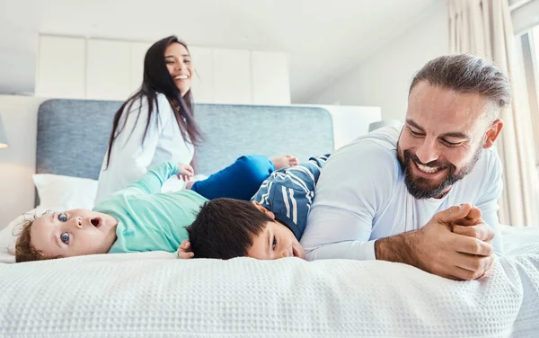 Happiness, smile and family being playful in the bedroom together of their modern house. Happy, love and excited children having fun, playing and bonding with their parents on the bed at their home
