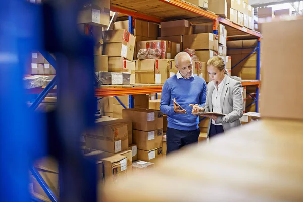 We always double check orders. a man and woman inspecting inventory in a large distribution warehouse