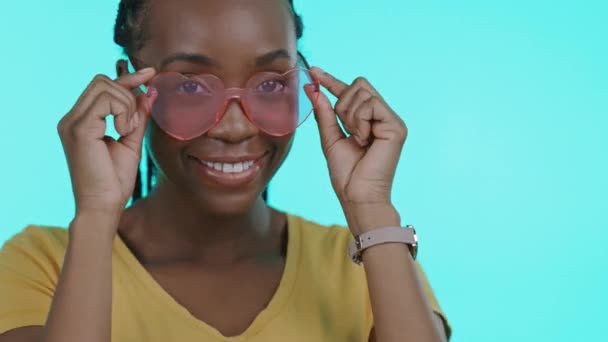 时尚和眼罩 一个黑人女人在工作室里闪烁着蓝色背景的太阳镜模型 与一位年轻貌美的女性在室内合影 微笑及时尚 以推广品牌色彩 — 图库视频影像
