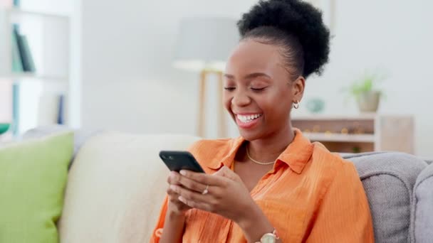 快乐而又黑的女人躺在沙发上 一边在客厅里一边打字一边发短信 微笑和非洲女性用手机在社交媒体上建立网络 浏览或滚动 — 图库视频影像