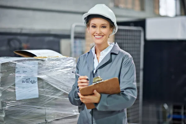 Feeling good about my job. A woman wearing a hardhat smiling at the camera in a factory