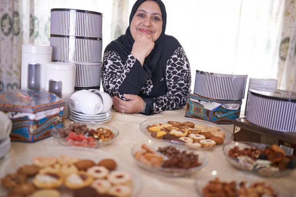 每个人的东西 一个成熟的穆斯林妇女坐在各种甜饼前 — 图库照片