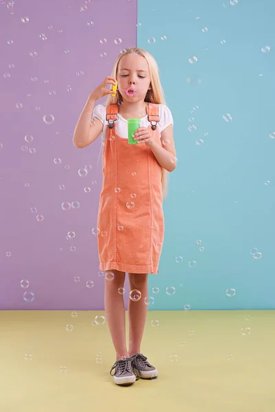 Διασκεδαστικό Ένα Χαριτωμένο Κοριτσάκι Φυσάει Φυσαλίδες Ένα Πολύχρωμο Φόντο — Φωτογραφία Αρχείου