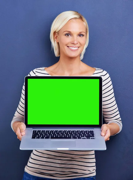 Have a browse. Studio shot of a young woman holding up a laptop with a chroma key screen