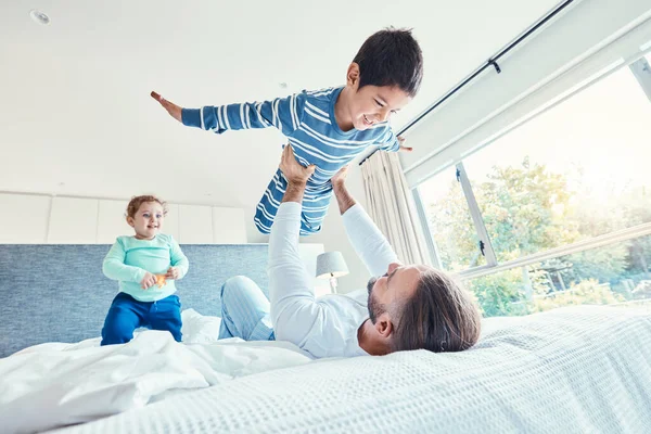 Love, father and kid in air, bed and quality time on break, happiness or bonding together. Family, dad or lifting boy in bedroom, cheerful or playing with joy, game or freedom with affection or smile.