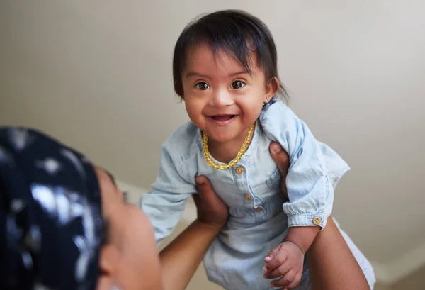 stock image Happy, down syndrome baby and child mom care of a woman holding a kid with a disability at a house. Happiness and smile of a young toddler special needs face from India in a home with a mother.