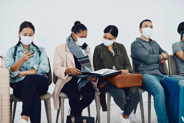 Immigration during covid with people traveling and waiting at an airport lounge during the pandemic. Foreign refugees in a public travel facility or border wearing masks in a corona virus outbreak.
