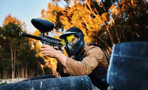 Paintball man with gun shooting target in forest battlefield, competition or games for fun adventure training. Aiming skill of male player or sports person in military focus or woods survival mission.