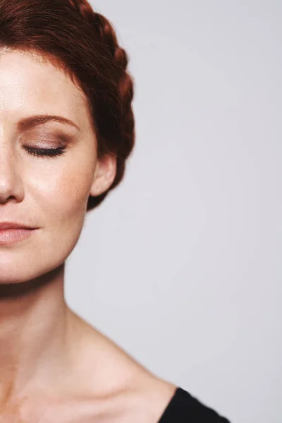 stock image Not a hair out of place. Studio shot of a beautiful redhead woman with a braided up-do posing against a gray background