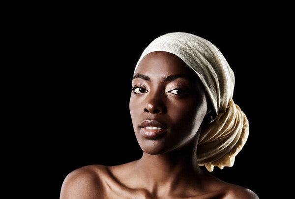 Her perfection is in her complexion. Studio shot of a beautiful woman wearing a headscarf against a black background