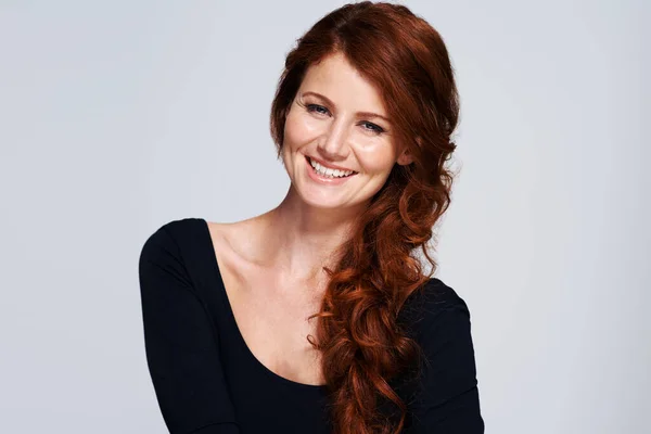 stock image Stylish strands. Studio shot of a young woman with beautiful red hair posing against a gray background