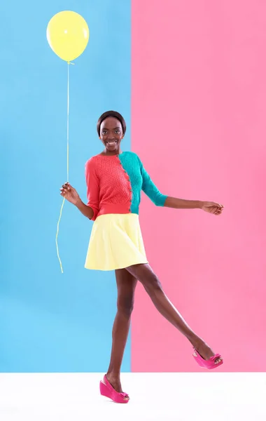 誰かを カラフルな背景を持つ黄色の風船を持つスタイリッシュな若い女性のスタジオショット — ストック写真