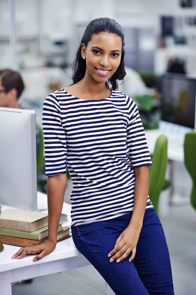Shes ready for a busy day. Portrait of an attractive young woman leaning on her desk at work