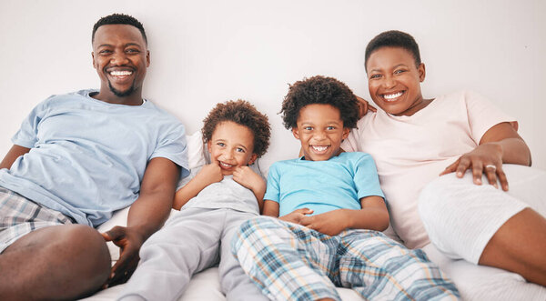 Black family, smile and portrait of parents with children on bed for bonding, quality time and relax together. Love, happy and African mom, dad and kids in bedroom enjoy morning, weekend and holiday.