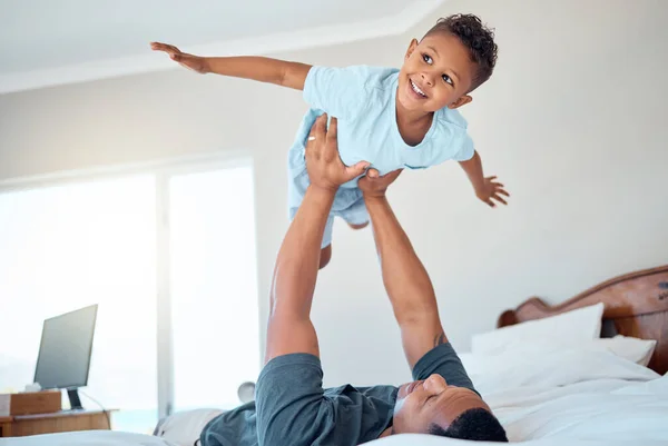 Father lifting kid in air in the bedroom having fun, playing and enjoying morning together. Bonding, love and dad holding young child in bed to pretend to fly for quality time and relax with family.