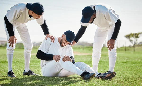 Baseball, team help and man with injury on field after accident, fall or workout in match. Sports, training and male player with fibromyalgia, inflammation pain or broken knee with friends helping