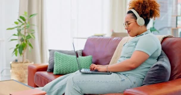 音乐耳机 笔记本电脑打字和坐在客厅沙发上的黑人妇女 计算机和快乐的远程工作者在家里的休息室里一边工作一边在沙发上播放收音机或播客 — 图库视频影像