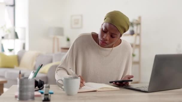 自宅のオフィスでフリーランスのプロジェクトを計画しながらノートを書くノートパソコン レポート作成中に携帯電話に関する研究を行う技術 ノートブック アフリカの女性フリーランサー — ストック動画