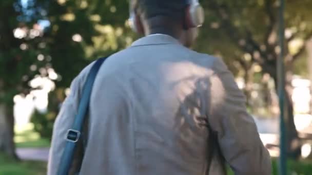 音乐和经商的黑人男子在公园里散步 以快乐 积极的态度和自由地工作 城市上下班时听收音机 田径和音频的男工的舞蹈 耳机和后背 — 图库视频影像