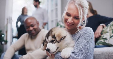 Arkadaşları, ailesi ve köpekli bir kadın aile evinde Noel partisinde oturma odasında. Arkadaşlık, çeşitlilik ve köpek sevgisi, mutlu bir kadın gülümsemesi ve yeni evcil hayvanı olan apartman dairesinde.