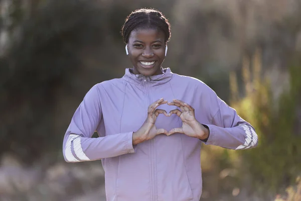 Black woman, fitness and hands in heart gesture, sign or symbol in love for healthy cardio, exercise or workout in nature. Portrait of African American female showing hearty shape hand for wellness.