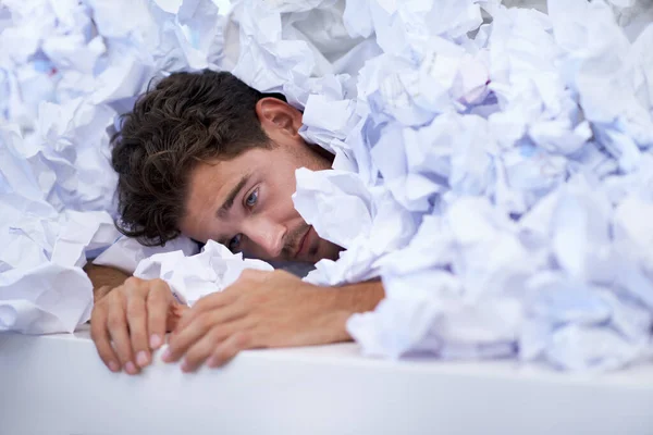 stock image Hes almost given up. a businessman buried under a pile of crumpled up paperwork