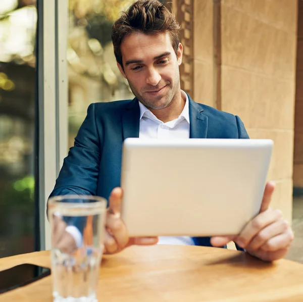 最新の事業動向については こちらをご覧ください 屋外のカフェでコーヒーを飲みながらデジタルタブレットを使っている若いビジネスマン — ストック写真