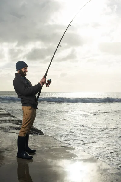 大きなキャッチのために彼の時間を取る 海の桟橋から一人の漁師が釣りをしていて — ストック写真