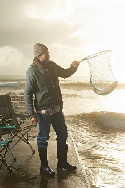 一大早的收获 在网中抓鱼的年轻渔夫 — 图库照片
