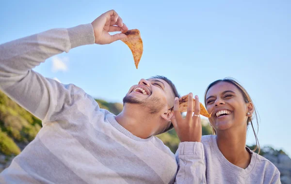 Pizza, comic and couple of friends in nature, lunch freedom and happy on a date in Portugal. Food love, funny and man and woman with fast food eating in a park, hungry and smile on a picnic in summer.