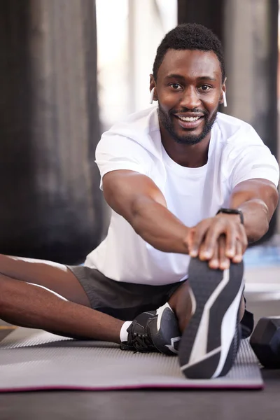 stock image Fitness, stretching and portrait of black man in gym for exercise, workout and training with earphones. Sports, healthy lifestyle and male athlete getting ready, warm up and stretch legs on floor.