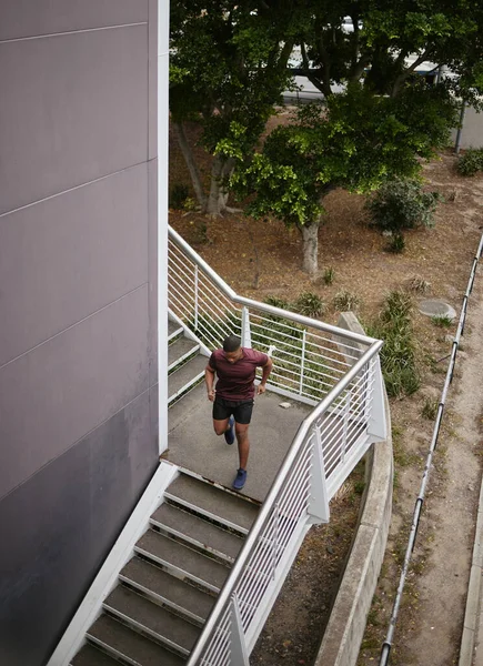 stock image Running, fitness and training with man on stairs for sports, workout and cardio endurance. Mindset, challenge and focus with runner on steps of building for speed, exercise and sports marathon.