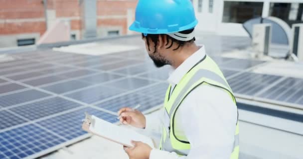工程师和检查太阳能电池板与剪贴板检查清单或质量保证的屋顶 非裔美国男性承包商检查城市屋顶的可持续电力或能源 — 图库视频影像