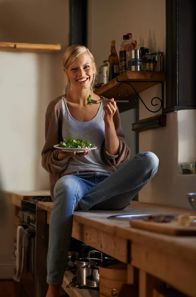 享受一个懒洋洋的下午与沙拉 一个年轻女人坐在厨房柜台边吃沙拉 — 图库照片
