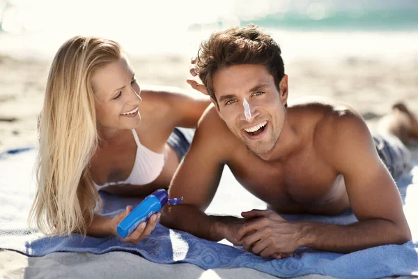 彼らは常に彼らの日焼け止めを置くことを確認 ビーチで日焼け止めを塗る若いカップル — ストック写真