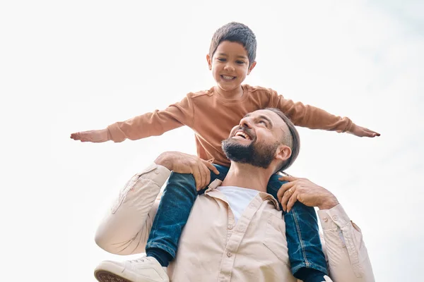 stock image Family, kids and boy sitting on the shoulders of his father outdoor while bonding from below. Fun, children and love with a man carrying his son outside while spending time together being playful.