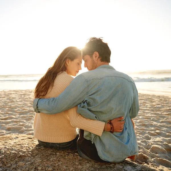 他们在海滩上找到了一个浪漫的地方 在海滩上 一对相依为命的年轻夫妇坐在一块巨石上的背景图片 — 图库照片