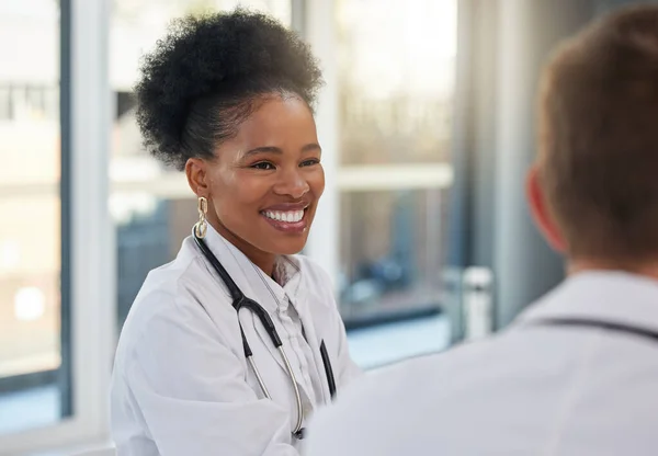 Doctor, happy black woman and meeting healthcare team for hospital management, medicine and discussion. Female surgeon, smile and talking to employees in collaboration, surgery and medical planning.
