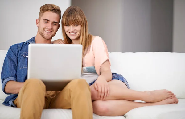 Using their laptop from the comfort of the couch. A young couple using a laptop while relaxing on the couch