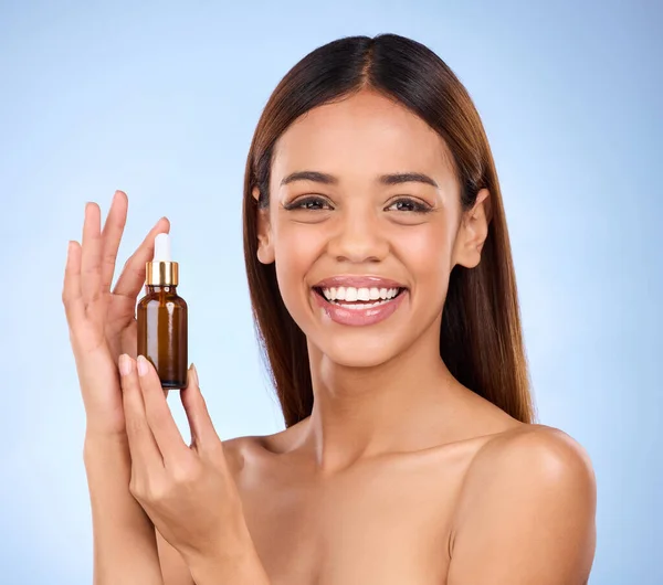Skincare, beauty and portrait of happy woman with serum for anti aging or skin glow on blue background. Cosmetics, facial repair and face of model with solution or collagen product on blue background.