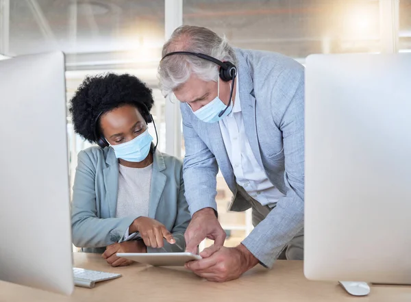 stock image Covid, crm and employees with tablet, mask and senior man helping black woman at call center help desk. Compliance, consulting and opinion, crm data for medical advisory agency with coaching support