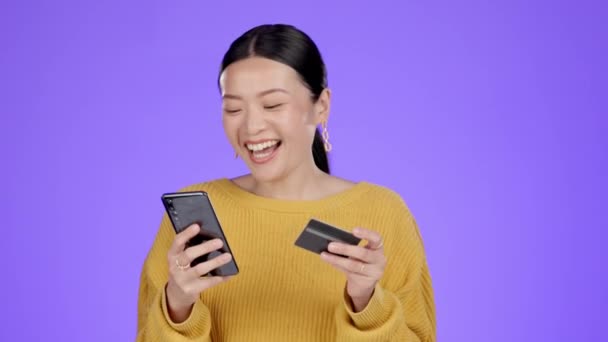 兴奋的女人带着信用卡和电话 在紫色背景下进行网上购物 笑和亚洲客户对移动购物 网上支付或电子商务感到满意 — 图库视频影像