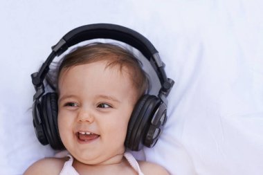 Müziğin zevklerini keşfetmek. Kulaklıkla müzik dinlerken gülen tatlı bir kız bebek.