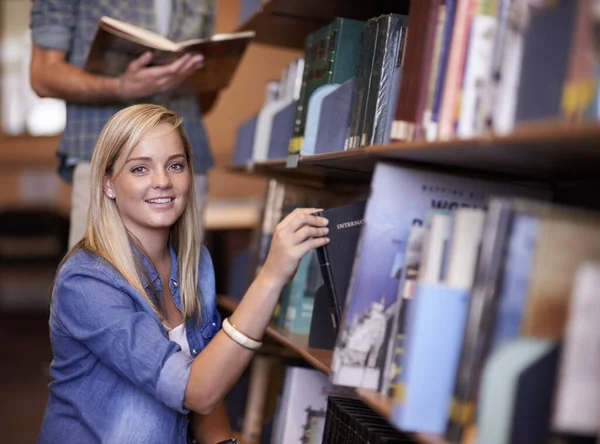 古いやり方を研究しています 図書館の棚から本を手に入れた若い女性 — ストック写真