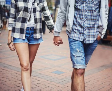 Romantik bir gezinti. Asfaltlı bir sokakta el ele yürüyen bir çiftin kırpılmış görüntüsü.