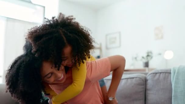 ピギーバックと一緒にソファの上で娘と母親に抱擁し 彼らの家で遊ぶ ソファの上の女の子と親 ゲームと楽しい週末にリラックス — ストック動画