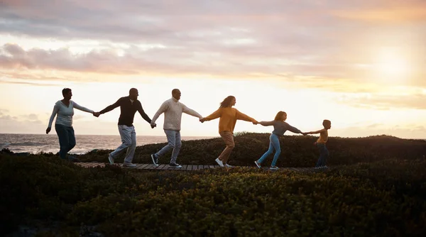 在日落时 家人牵着手 在大自然中散步 共同寻求集体支持 成长发展和冒险 与祖父母在一起的儿童 为了健康 健康和在公园小径或海洋边奔跑 — 图库照片