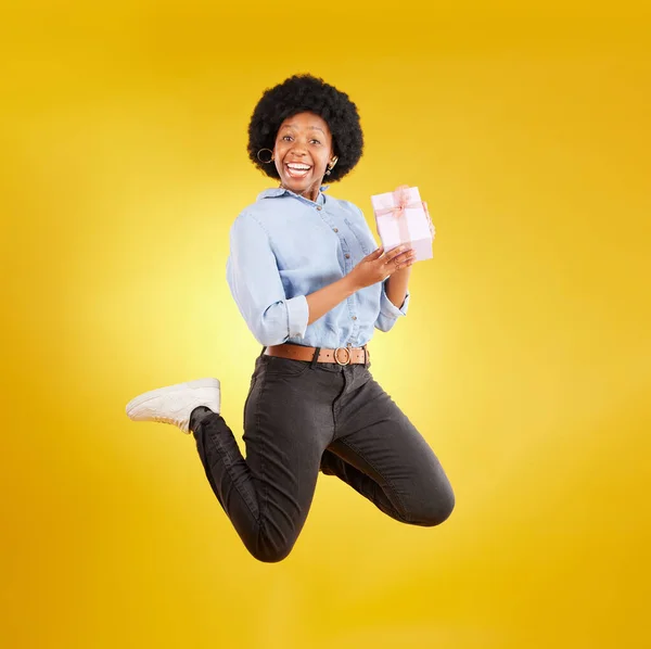 兴奋而又黑的女人带着天赋在黄色的背景下 精力充沛 在演播室里开心的笑着 生日模拟 庆祝和孤立的女孩跳与礼物 盒子和惊喜包 — 图库照片