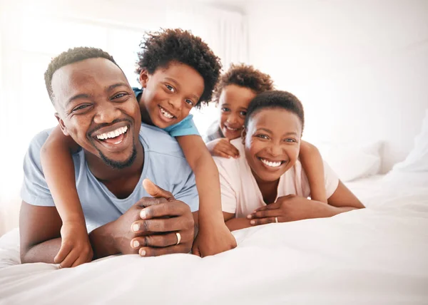 Happy, laughing and portrait of a black family on a bed for playing, quality time and comfort. Bonding, love and African children with parents in bedroom for happiness and relaxation in the morning.
